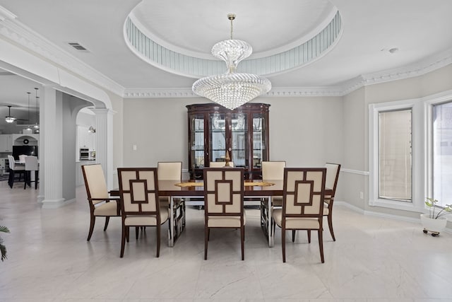 dining room with ceiling fan with notable chandelier, a raised ceiling, ornamental molding, and decorative columns