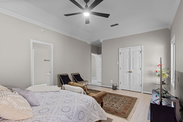 bedroom featuring light hardwood / wood-style floors, ceiling fan, ornamental molding, and ensuite bathroom