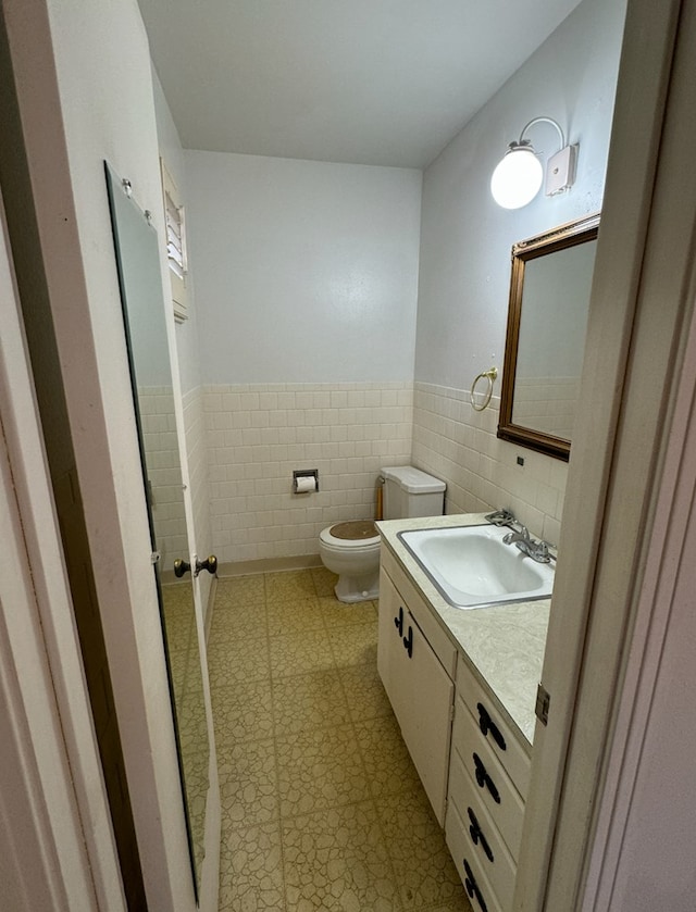 bathroom featuring vanity, tile walls, and toilet