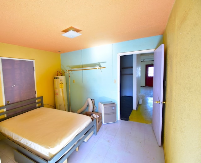 bedroom with a textured ceiling, gas water heater, and a closet