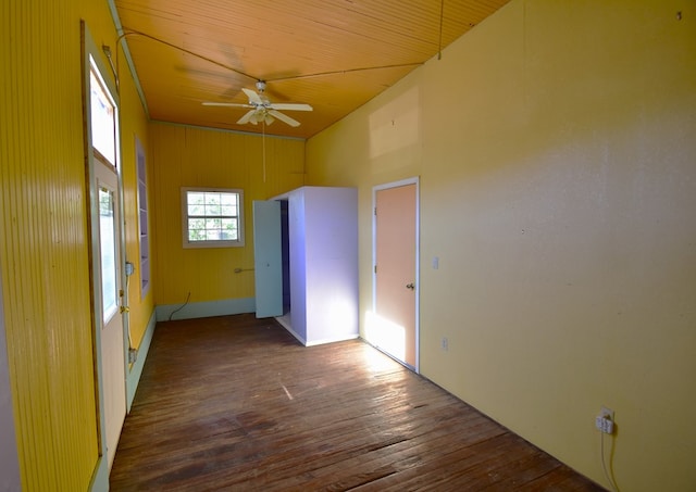 spare room featuring ceiling fan, wooden ceiling, a high ceiling, dark hardwood / wood-style floors, and wood walls