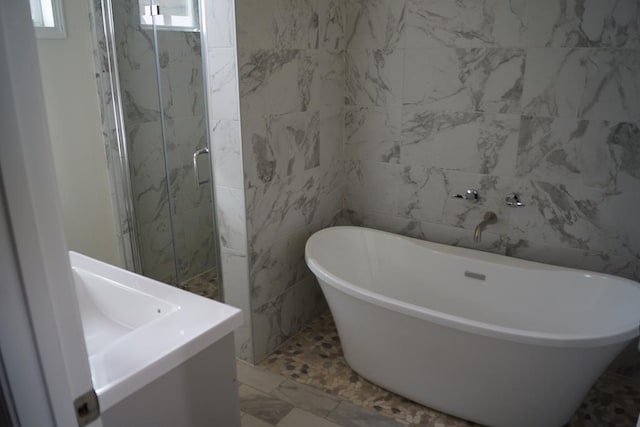 bathroom featuring plus walk in shower, tile walls, and vanity