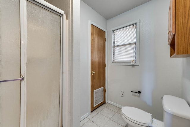 bathroom featuring tile patterned floors, toilet, and a shower with door