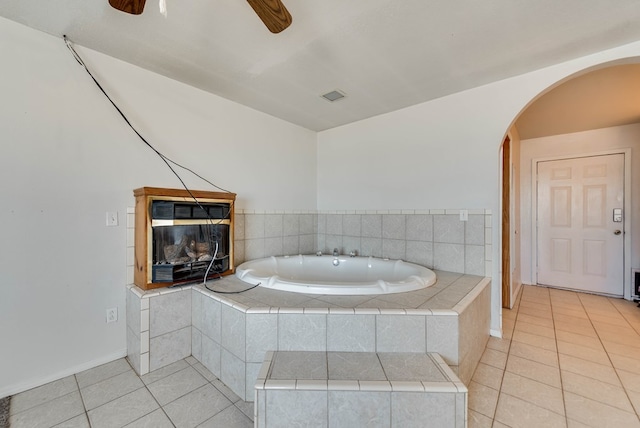 bathroom with tile patterned flooring, tiled bath, and ceiling fan