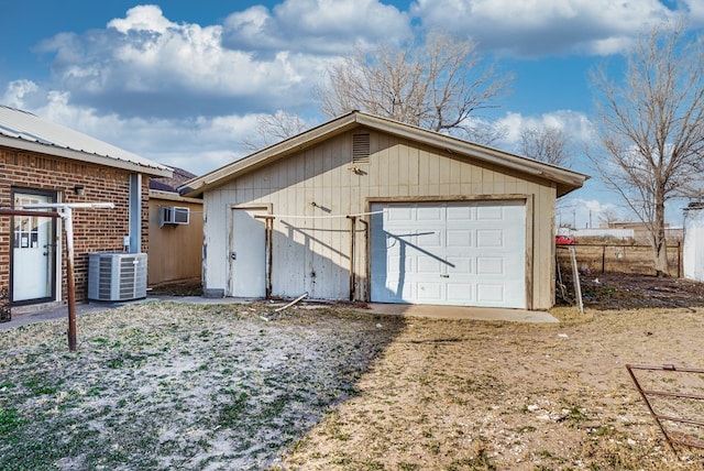 view of outdoor structure with a garage, a wall mounted AC, and cooling unit