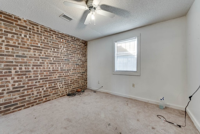 spare room with carpet flooring, ceiling fan, a textured ceiling, and brick wall