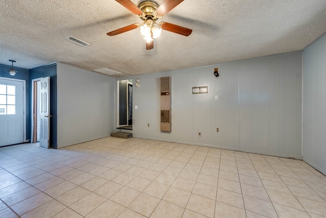 tiled spare room with ceiling fan, wooden walls, and a textured ceiling