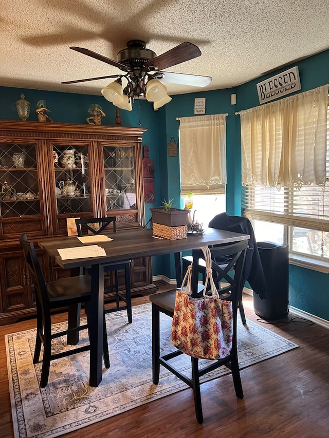 dining space featuring wood-type flooring, a textured ceiling, and ceiling fan