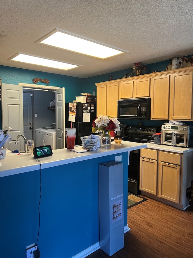 kitchen featuring washing machine and dryer, dark wood-type flooring, black appliances, and a textured ceiling