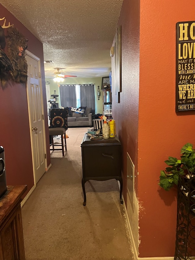 hall with carpet flooring and a textured ceiling