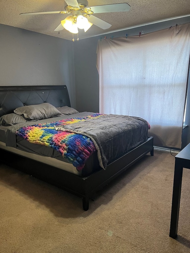 carpeted bedroom featuring ceiling fan and a textured ceiling