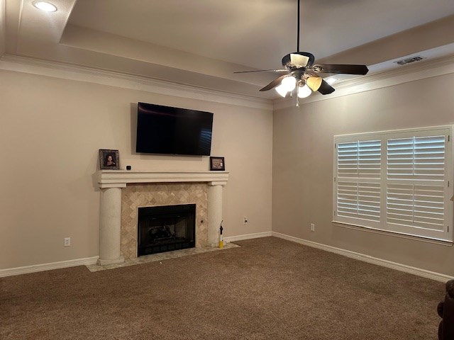 unfurnished living room with a fireplace, carpet flooring, visible vents, ornamental molding, and a raised ceiling