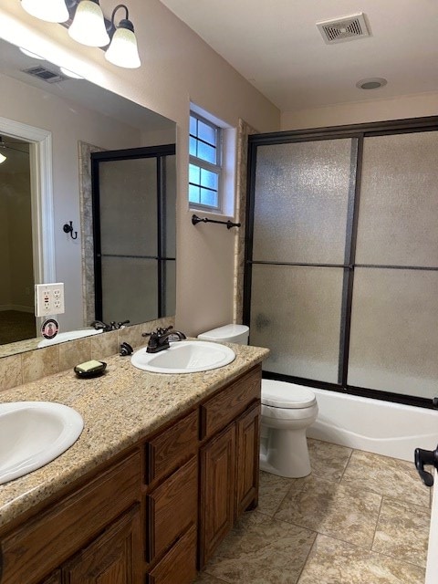 full bathroom with toilet, double vanity, a sink, and visible vents