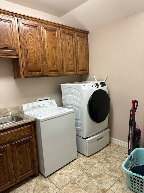 washroom with cabinet space, a sink, baseboards, and separate washer and dryer