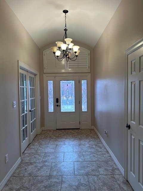 foyer entrance featuring vaulted ceiling, a chandelier, and baseboards