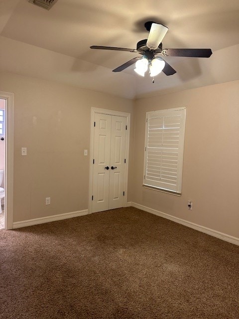 carpeted empty room with ceiling fan and baseboards