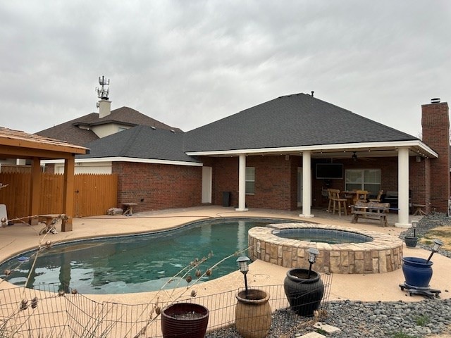 view of swimming pool featuring a patio, fence, and a pool with connected hot tub