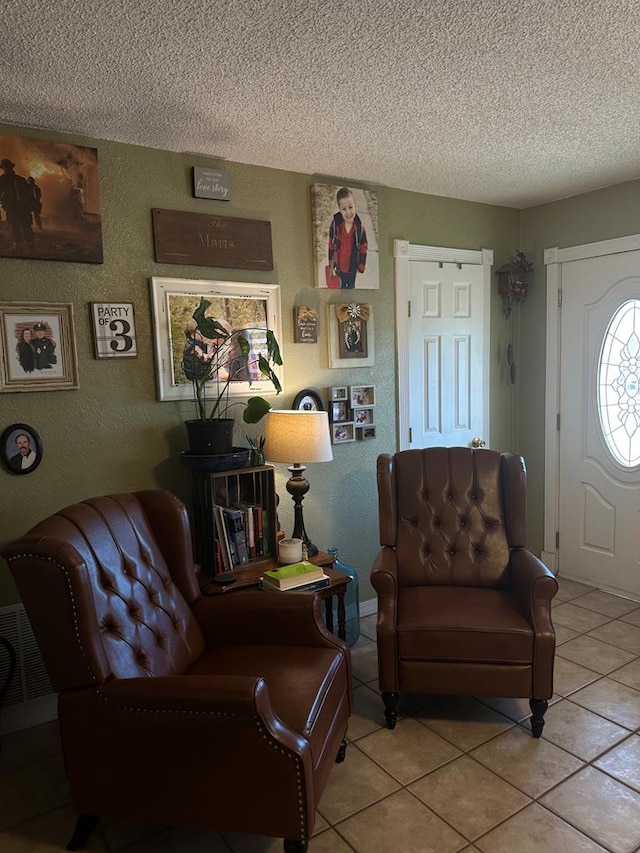 living room with light tile patterned floors, a textured ceiling, and a textured wall