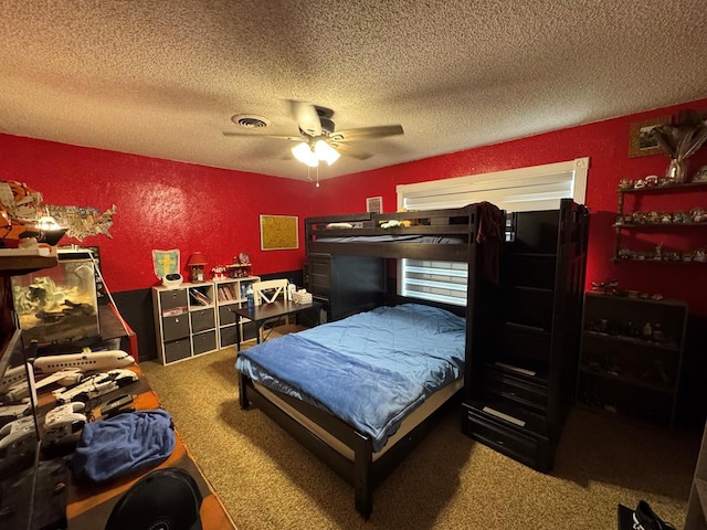 bedroom with visible vents, a textured wall, ceiling fan, a textured ceiling, and carpet flooring