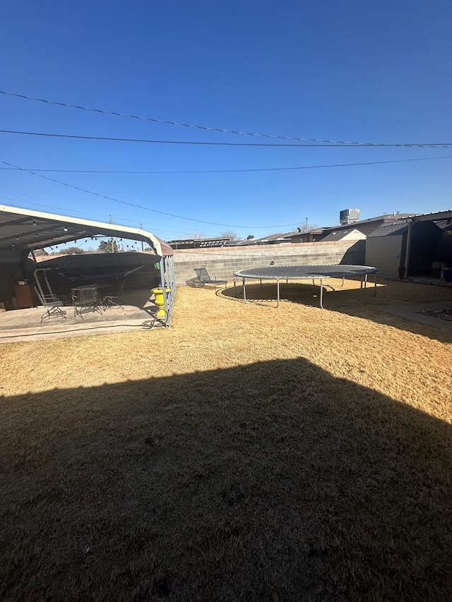 view of yard with a trampoline and fence