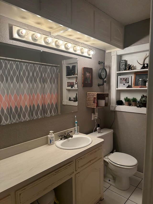 bathroom with a textured wall, toilet, a shower with shower curtain, tile patterned floors, and vanity