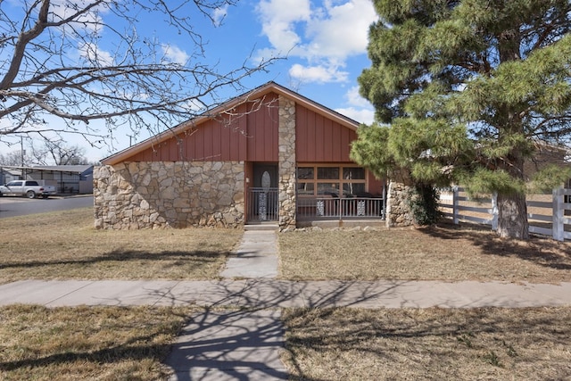 mid-century inspired home with a porch, fence, and stone siding