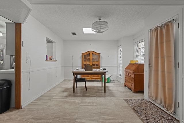 office area with a skylight, visible vents, and a textured ceiling