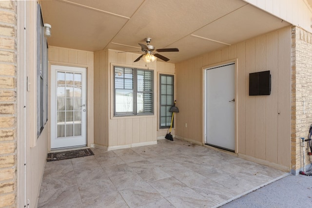 entrance to property with a patio area, ceiling fan, and brick siding