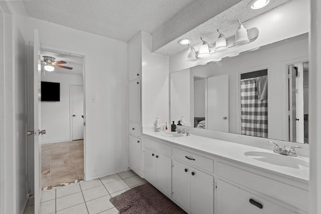 full bath featuring double vanity, a textured ceiling, a sink, and tile patterned floors