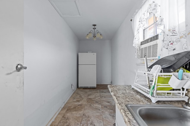 kitchen with a sink, freestanding refrigerator, and baseboards