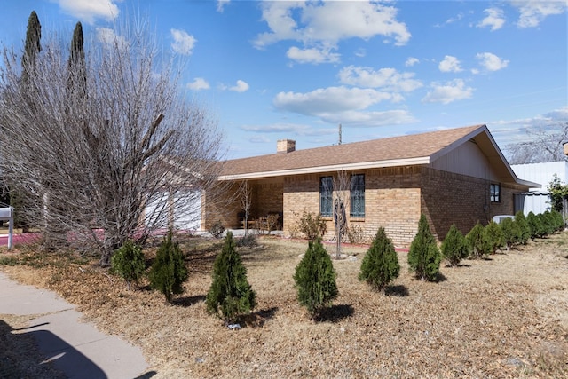 view of side of home featuring a garage, brick siding, a chimney, and roof with shingles