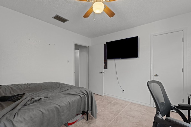 bedroom featuring a ceiling fan, visible vents, a textured ceiling, and light tile patterned flooring