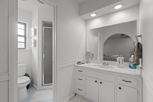 full bathroom featuring a stall shower, a textured ceiling, toilet, and vanity