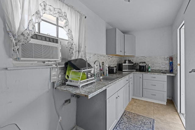 kitchen featuring light tile patterned flooring, cooling unit, a sink, decorative backsplash, and stainless steel microwave