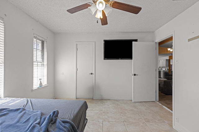 bedroom featuring light tile patterned floors, ceiling fan, and a textured ceiling