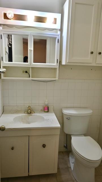 bathroom with vanity, tile patterned floors, toilet, tile walls, and tasteful backsplash