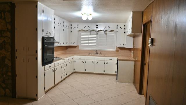 kitchen with oven, white cabinetry, and sink