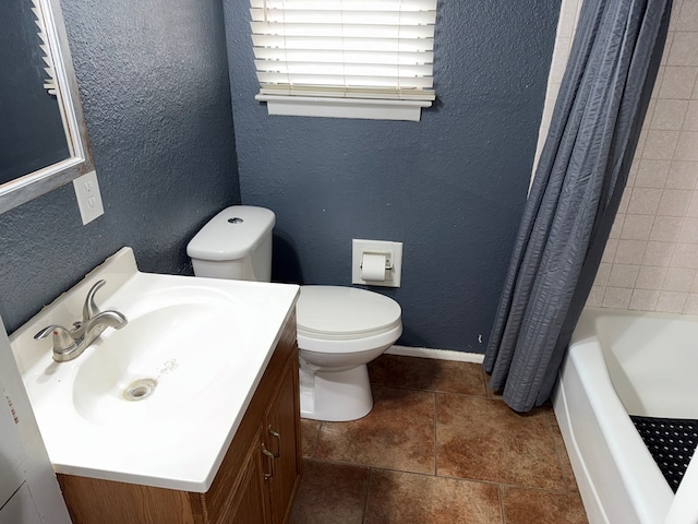 full bath featuring vanity, toilet, a textured wall, and baseboards