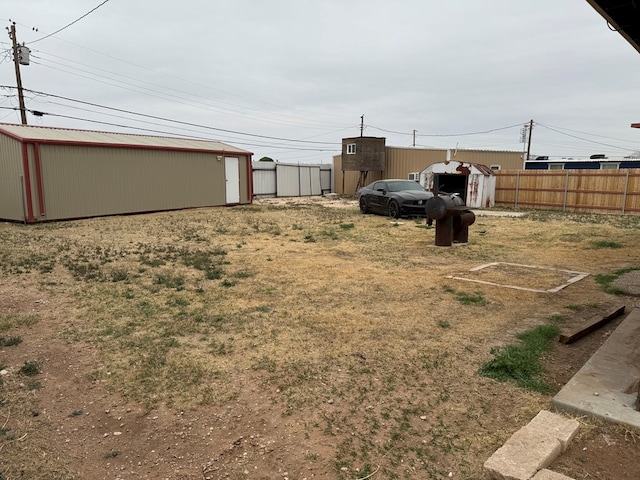 view of yard with an outbuilding, a storage unit, and fence