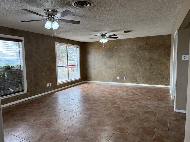 empty room with a ceiling fan, a healthy amount of sunlight, and visible vents