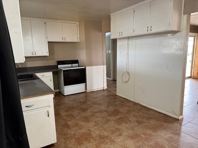 kitchen featuring a sink, electric range, dark countertops, and white cabinetry