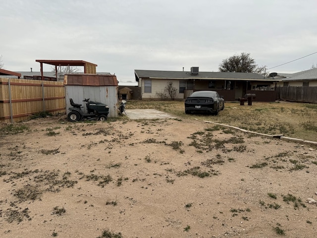 view of yard featuring a storage shed, an outbuilding, central air condition unit, and fence