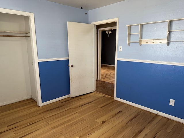 unfurnished bedroom with a closet, baseboards, and wood finished floors