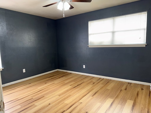 spare room with baseboards, wood finished floors, and ceiling fan