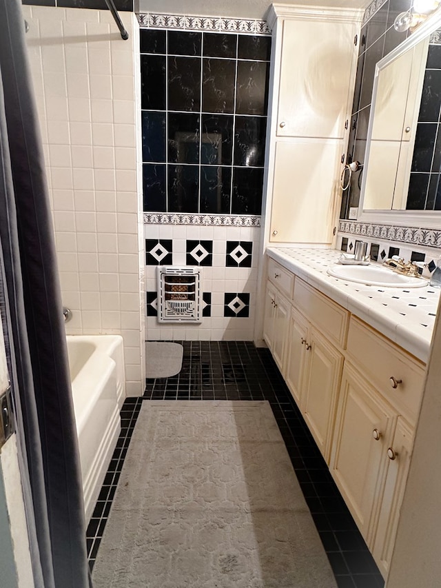 bathroom featuring tile patterned flooring, a tub to relax in, vanity, and tile walls