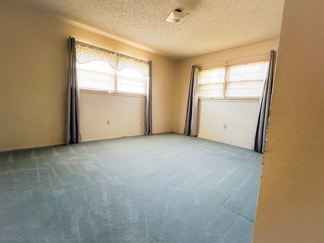 carpeted empty room with a textured ceiling