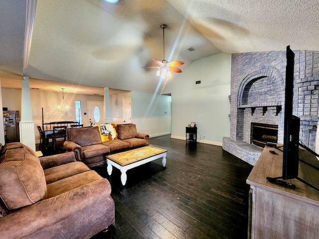 living room featuring lofted ceiling, ceiling fan, a textured ceiling, a brick fireplace, and dark wood finished floors