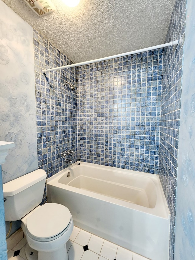 full bathroom with bathtub / shower combination, visible vents, toilet, a textured ceiling, and tile patterned floors