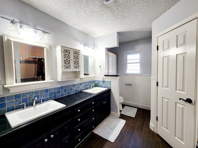 full bath featuring a wainscoted wall, wood finished floors, a sink, and toilet