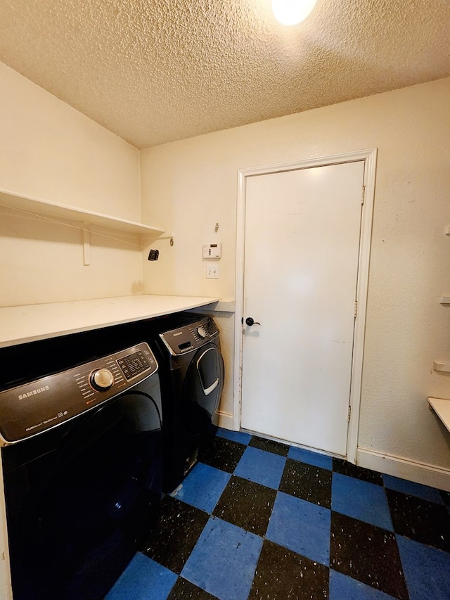 washroom featuring a textured ceiling, dark floors, laundry area, baseboards, and washing machine and clothes dryer